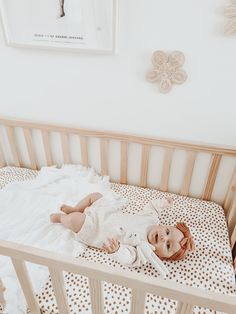 a baby laying in a crib next to a wall