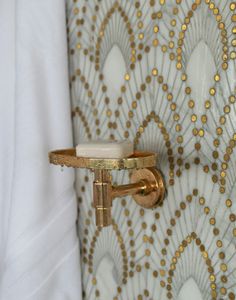 a close up of a door handle on a white and gold wallpapered background