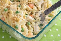 a glass casserole dish filled with pasta and peas, topped with a serving spoon