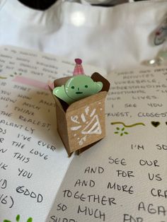 an origami box with a birthday candle inside on top of a handwritten note