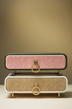 a pink and white purse sitting on top of a wooden table next to a gold ring