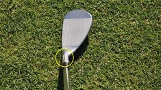 a close up of a golf club on the grass with a yellow circle around it