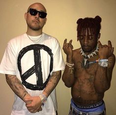 two men standing next to each other in front of a wall with peace signs on it