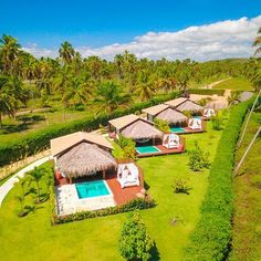 an aerial view of the resort with swimming pool and thatched roof huts, surrounded by palm trees