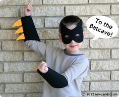 a young boy wearing a black mask and holding up two fingers with an orange bat on it