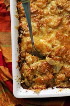 a spoon is in a casserole dish with meat and cheese