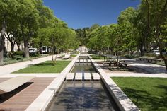 an empty park with benches and water features in the center, surrounded by green trees