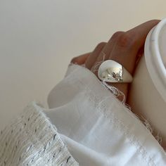 a person's hand holding a white ring with a diamond in the middle and a button on it