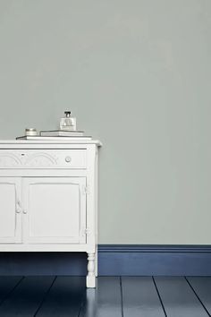 a white sink sitting on top of a wooden cabinet next to a gray wall and blue floor