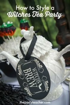 a tea party with black and white decorations on the table, including an old fashioned teapot