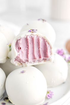 some white chocolate eggs with pink frosting on top and purple flowers around the edges