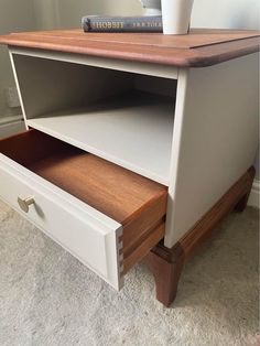 a white desk with two drawers and a book shelf on top of the drawer is shown