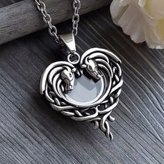 "This beautiful double horse head locket necklace is the perfect way to keep your cherished memories close to your heart. It features an intricate celtic design. This makes it a special keepsake for anyone who has lost a loved one or horse and wants to keep a piece of their beloved  with them always. Your keepsake is nicely displayed through the glass.  *The locket can hold a small amount of horse hair nicely wound inside it, or cremation ashes. It is made of high-quality stainless steel and glass. It comes with a 24-inch stainless-steel cable chain with a lobster clasp closure. *This horse memorial locket would make a thoughtful gift for anyone who loves horses or wants to commemorate a special person or equine companion. Enter my shop: Www.thoughtfullkeepsakes.etsy.com  *Size: Pendant ab Horse Keepsake, Hair Locket, Horse Memorial, Hair Necklace, Mustang Horse, Keepsake Gifts, Urn Jewelry, Urn Necklace, Memory Locket