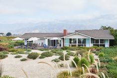 a beach house with an ocean view and sand dunes in the foreground, surrounded by greenery