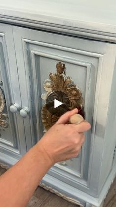 a person is holding something in their hand and pointing to the cabinet with it's door open