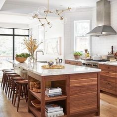 a kitchen with wooden floors and an island in front of a stove top oven surrounded by chairs