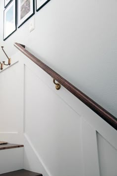 stairs with pictures hanging on the wall and wooden handrails in front of them