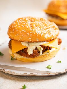 a cheeseburger with meat and lettuce is on a plate next to another sandwich