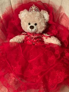 a teddy bear in a red dress with a tiara on it's head