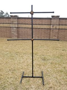 a black metal pole with four bars on it in the middle of a grassy field