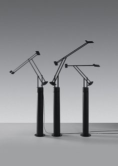 three black and white lamps on top of each other in front of a gray background