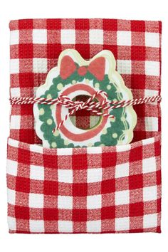 a red and white checkered napkin with a christmas cookie in the pocket on it