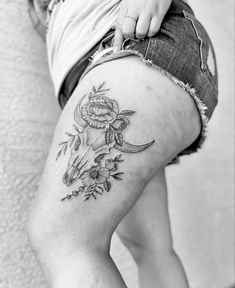 black and white photo of a woman's thigh with tattoos on her legs,