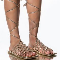 Flat Sandal In Gold Features A Vegan Leather Construction, A Flat Sole, A Strappy Lace Up Silhouette, An Open Square Toe, And A Wide Basket Woven Upper. Fit And Details Approx. Measured From A Women’s Size 8: - Open Toe - 35” Lace Length - Strappy Upper - Lace-Up Fit - Imported Gold Ankle Strap Lace-up Sandals For The Beach, Gold Strappy Lace-up Sandals, Gold Lace-up Sandals With Ankle Strap For Beach, Gold Lace-up Ankle Strap Sandals For The Beach, Adjustable Gold Sandals For Beach Season, Gold Open Toe Lace-up Beach Sandals, Gold Lace-up Sandals With Round Toe For Beach, Gold Strappy Lace-up Sandals For Vacation, Gold Lace-up Sandals For Beach