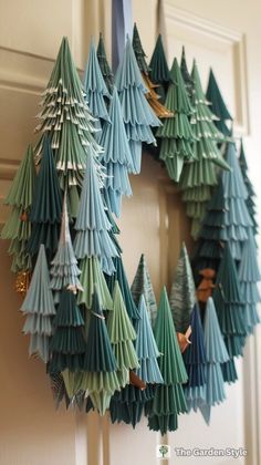 an origami christmas wreath hanging on the front door with trees cut out of it