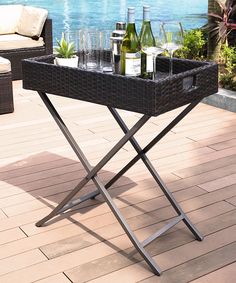 a table with two bottles of wine and glasses on it sitting on a deck next to a couch