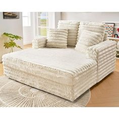 a large white couch sitting on top of a wooden floor next to a chair and rug