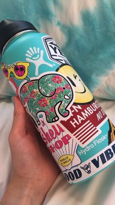 a person is holding a water bottle with stickers on it and the lid has an elephant