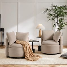 a living room with two chairs and a table in front of a plant on the floor