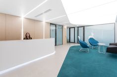 a woman is sitting at the reception desk in an office building with blue carpet and white walls