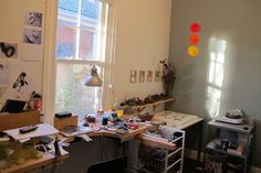 a cluttered room with various items on the desk and shelves in front of it