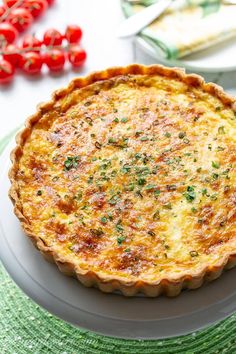 a quiche is sitting on a plate next to some tomatoes and other food items