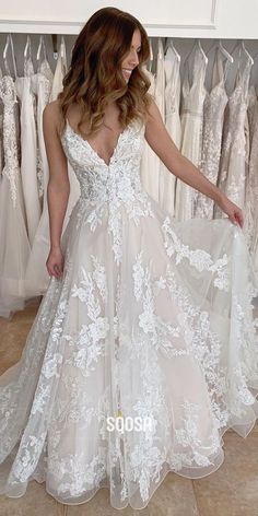 a woman standing in front of wedding dresses and looking at the dress she is wearing