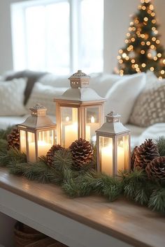 candles and pine cones on a mantle in front of a christmas tree