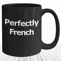 a black coffee mug with the words perfectly french on it sitting on a wooden table