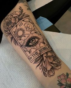 a woman's leg with an eye and flower tattoo on the side of her arm