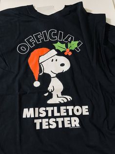 a black shirt with a snoopy christmas hat on it's chest and the words, official mistlet toe tester