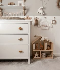 a baby's room with a white dresser and toy animals on the shelf next to it