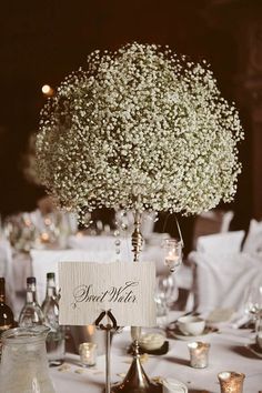 a centerpiece with baby's breath flowers is on top of a table at a wedding