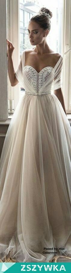 a woman in a wedding dress standing by a window with her hand on her hip