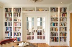 a living room filled with lots of furniture and bookshelves next to a doorway