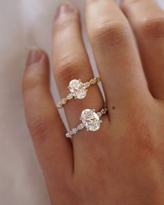 a woman's hand with two engagement rings on her left and the other hand