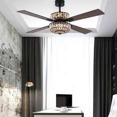 a living room with a ceiling fan and a desk in front of a large window