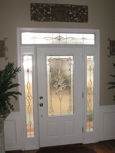 a white front door with two glass panels and a potted plant on the side