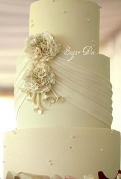 a three tiered wedding cake with flowers on top