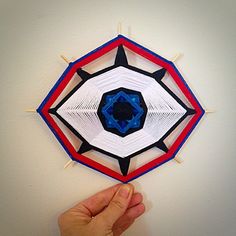 a hand is holding up a paper origami kite with blue, red and white shapes